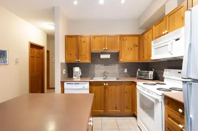 a kitchen with wooden cabinets and white appliances at Deer Run by Whistler Premier in Whistler