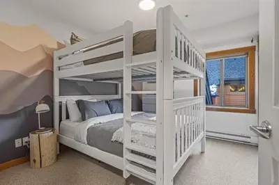 a bedroom with a white bunk bed and a window at Attractive Downtown Condo! Hot Tub, Mountain Views managed by Little Sister Getaways in Canmore