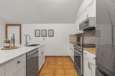 a kitchen with white cabinets and stainless steel appliances at Attractive Downtown Condo! Hot Tub, Mountain Views managed by Little Sister Getaways in Canmore