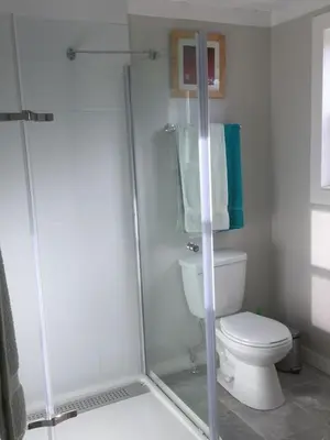 a bathroom with a shower and a toilet and towels at Cozy ,artistic cottage in a garden setting close to the beach and hiking trails. in Powell River