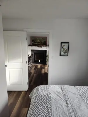 a bedroom with a bed and a room with a fireplace at Tranquil & Tasteful One Bdrm Private Suite NE in Edmonton