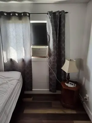 a bedroom with a bed and curtains and a lamp at Tranquil & Tasteful One Bdrm Private Suite NE in Edmonton