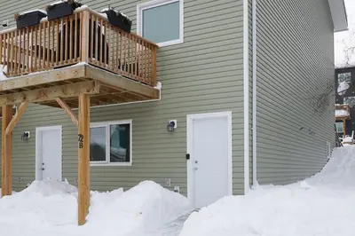 a house with a wooden deck in the snow at NN - The Névé - Crestview 1-bed 1-bath in Whitehorse
