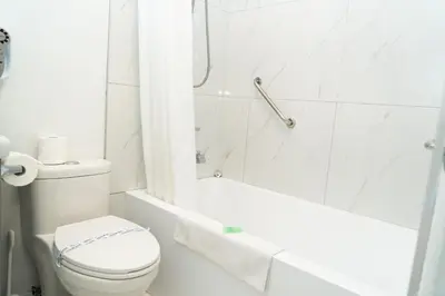 a white bathroom with a toilet and a bath tub at Mountain View Hope Motel in Hope