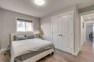 a bedroom with a bed and a window and a door at Rare Find fully renovated 6 bedroom 3 bath and both levels in Calgary