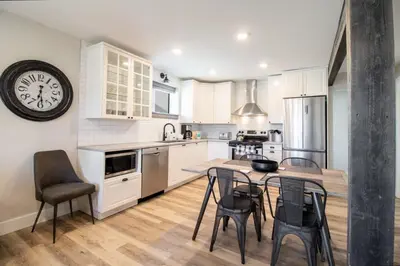 a kitchen with a table and chairs and a clock at NN - Flats on 4th #1 - Downtown 2-bed 2-bath in Whitehorse