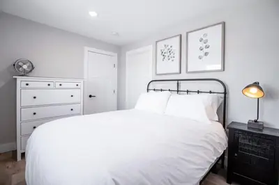 a white bedroom with a bed and a dresser at NN - Flats on 4th #1 - Downtown 2-bed 2-bath in Whitehorse