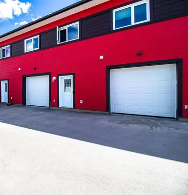 a red building with three garage doors on it at NN - Eddy #1 - Whistlebend 3-bed 2 5-bath in Whitehorse
