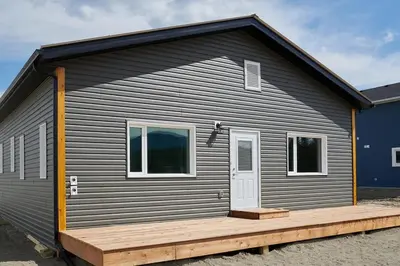 a gray house with a wooden deck in front of it at NN - The Kluane - Whistlebend 3-bed 2-bath in Whitehorse
