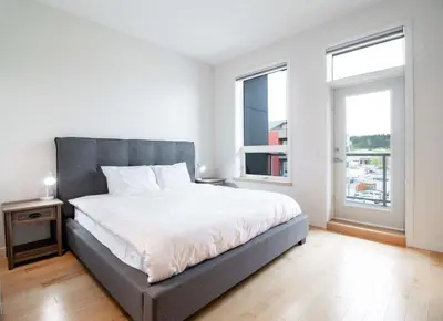 a bedroom with a large bed and two windows at NN - Park View #1 - Downtown 2-bed 2-bath in Whitehorse