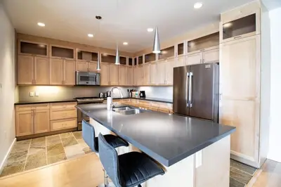 a kitchen with wooden cabinets and a stainless steel refrigerator at NN - Park View #1 - Downtown 2-bed 2-bath in Whitehorse
