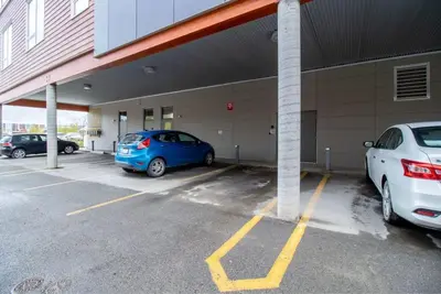 two cars parked in a parking lot next to a building at NN - Park View #1 - Downtown 2-bed 2-bath in Whitehorse
