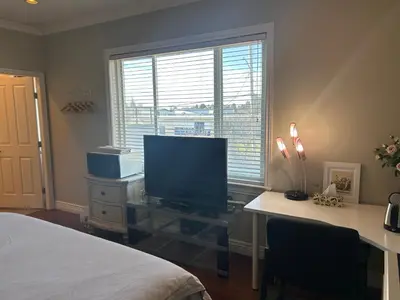 a bedroom with a desk with a television and a bed at independent entrance cozy room with private bathroom close to YVR Richmond in Richmond
