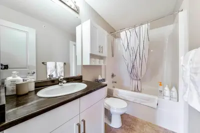 a white bathroom with a sink and a toilet at Bright Luxe Condo, AC, Top Floor, King Bed, Balcony! in Edmonton