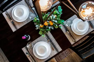 a wooden table with white plates and a vase of oranges at Bright Luxe Condo, AC, Top Floor, King Bed, Balcony! in Edmonton