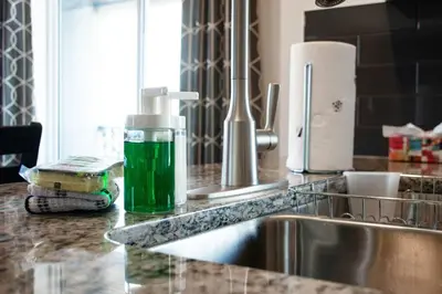 a bottle of green liquid sitting on a kitchen counter at Bright Luxe Condo, AC, Top Floor, King Bed, Balcony! in Edmonton