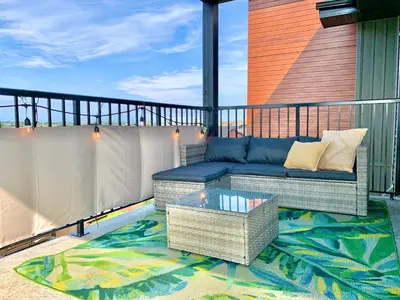 a patio with a couch and a table on a balcony at Peaceful Oasis Condo, AC, Top Floor, Secure UG Parking, Balcony, King Bed! in Edmonton