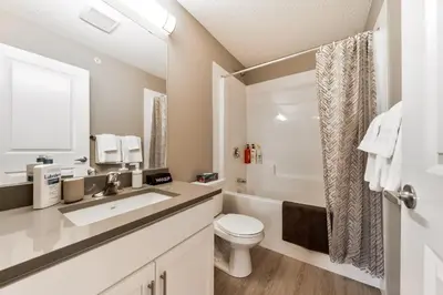 a white bathroom with a toilet and a sink at Peaceful Oasis Condo, AC, Top Floor, Secure UG Parking, Balcony, King Bed! in Edmonton
