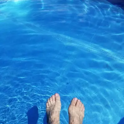 a person standing in the water with their feet in the water at Global Village Permaculture BnB in Oliver