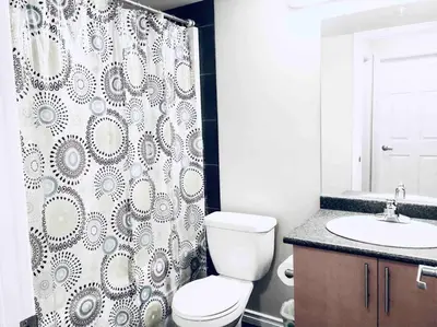 a bathroom with a toilet and a shower curtain at 2 BDRM A/C Condo w/Ensuite Laundry + Free Parking in Edmonton