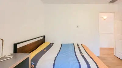 a bedroom with a bed in a room with white walls at Ocean Park B&B in Surrey