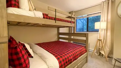 a bedroom with two bunk beds with a red plaid blanket at 2BR plus Loft, Modern and Spacious, Hot Tub and Sauna, Private Balcony, Fireplace in Whistler