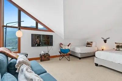 a living room with a blue couch and a bed at Whistler 'Treehouse' in Whistler