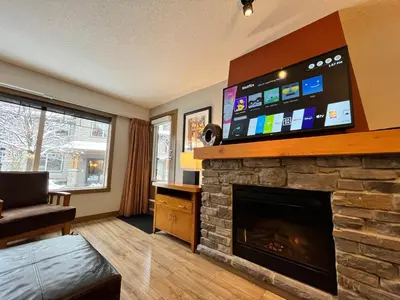 a living room with a fireplace with a flat screen tv at Perfect family 2-bed Condo with hot tub in Dead Man's Flats