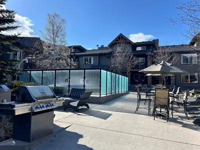 a patio with a grill and tables and chairs at Perfect family 2-bed Condo with hot tub in Dead Man's Flats