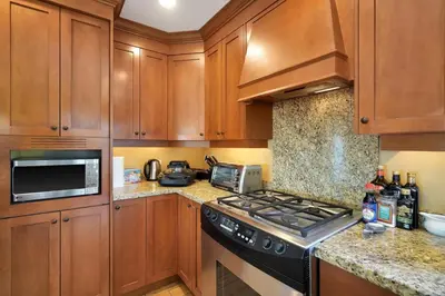a kitchen with wooden cabinets and a stove top oven at Great West Vancouver house with hot tub, across from beach & 10 mn to Downtown Vancouver in West Vancouver