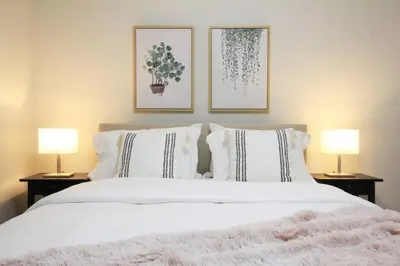 a bedroom with a large white bed with two lamps at Executive Bsmt Suite, King Bed, 5 min to DT & Whyte Ave, Sleeps 6! in Edmonton