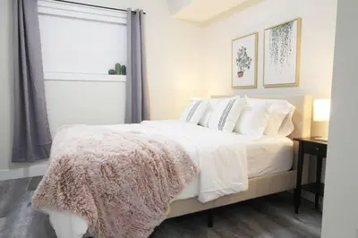 a bedroom with a bed with white sheets and pillows at Executive Bsmt Suite, King Bed, 5 min to DT & Whyte Ave, Sleeps 6! in Edmonton
