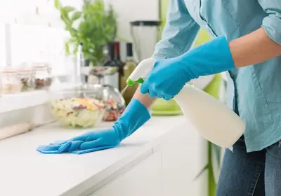 a woman in blue gloves cleaning a counter with a brush at Amazing Luxe Home, AC, HUGE Yard, FirePit, Pet Friendly, Sleeps 10! in Edmonton