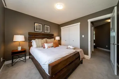 a bedroom with a large bed and a table with a lamp at Amazing Luxe Home, AC, HUGE Yard, FirePit, Pet Friendly, Sleeps 10! in Edmonton