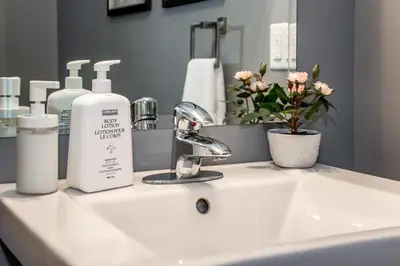 a bathroom sink with two bottles of soap and a mirror at Amazing Luxe Home, AC, HUGE Yard, FirePit, Pet Friendly, Sleeps 10! in Edmonton