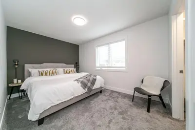 a bedroom with a large bed and a chair at Chic Hideaway, 5BR near DT, Fireplace, King Bed, Fast Wifi, Sleeps 13! in Edmonton