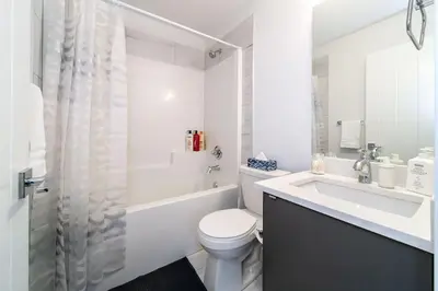 a white bathroom with a toilet and a sink at Chic Hideaway, 5BR near DT, Fireplace, King Bed, Fast Wifi, Sleeps 13! in Edmonton