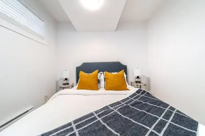a white bedroom with a bed with yellow pillows at Chic Hideaway, 5BR near DT, Fireplace, King Bed, Fast Wifi, Sleeps 13! in Edmonton