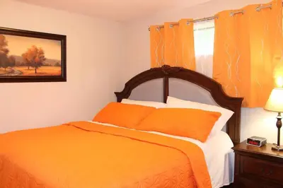 a bedroom with an orange bed and a window at 2-Bedroom basement suite with a separate entrance. in Abbotsford