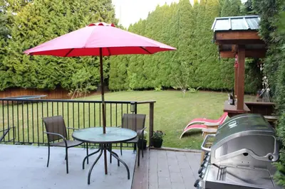a table with a red umbrella and a grill at 2-Bedroom basement suite with a separate entrance. in Abbotsford