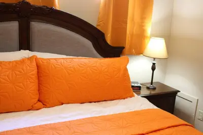 a bed with orange pillows and a table with a lamp at 2-Bedroom basement suite with a separate entrance. in Abbotsford