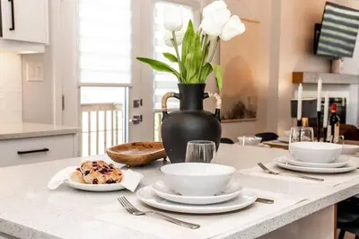 a table with plates of food and a vase with flowers at Nordic Retreat, 4BR, Min to WEM & DT, AirCon & Fireplace, Sleeps 10! in Edmonton
