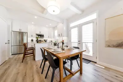 a kitchen and dining room with a wooden table and chairs at Nordic Retreat, 4BR, Min to WEM & DT, AirCon & Fireplace, Sleeps 10! in Edmonton