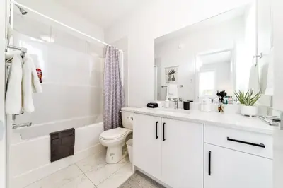 a white bathroom with a toilet and a tub and a sink at Nordic Retreat, 4BR, Min to WEM & DT, AirCon & Fireplace, Sleeps 10! in Edmonton