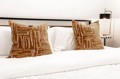 a bed with brown pillows and white sheets at Nordic Retreat, 4BR, Min to WEM & DT, AirCon & Fireplace, Sleeps 10! in Edmonton