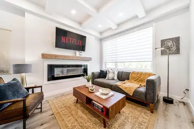 a living room with a couch and a fireplace at Modern Nordic Escape, 3BR Near WEM & DT, AirCon & Fireplace, Wifi, Sleeps 6! in Edmonton