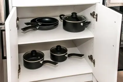 four pots and pans on a shelf in a kitchen at Modern Nordic Escape, 3BR Near WEM & DT, AirCon & Fireplace, Wifi, Sleeps 6! in Edmonton