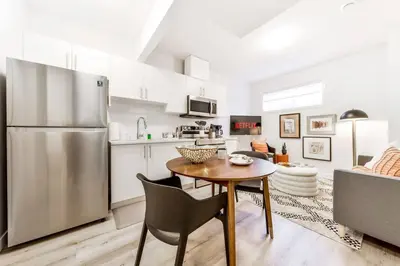 a kitchen with a table and a stainless steel refrigerator at Cozy Nordic Utopia, Bsmt Suite near WEM & DT, King Bed, WiFi in Edmonton