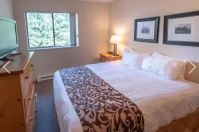 a hotel room with a large bed and a television at Whistler Steps to Village Sleeps 8 + Jacuz + Park in Whistler