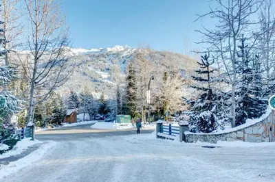 a person walking down a snow covered road with a mountain at Whistler Steps to Village Sleeps 8 + Jacuz + Park in Whistler